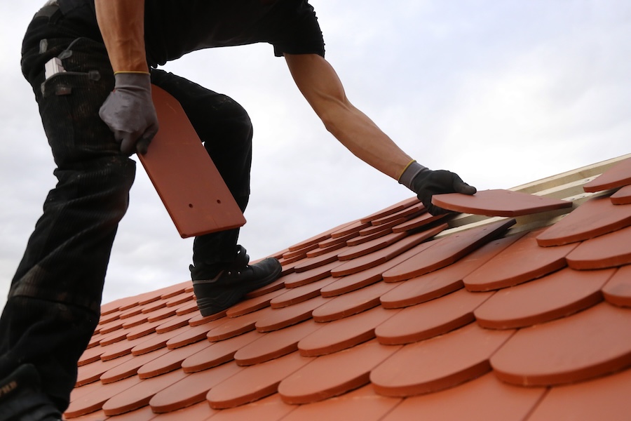 A roofer repairing a tiled roof