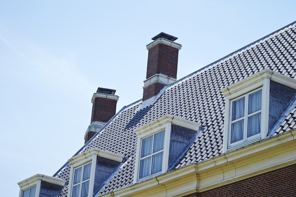 Low angle photo of a gable roof with the blue sky in the background