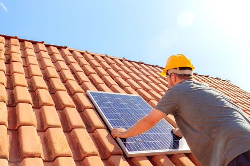 A man installing a solar panel on a roof